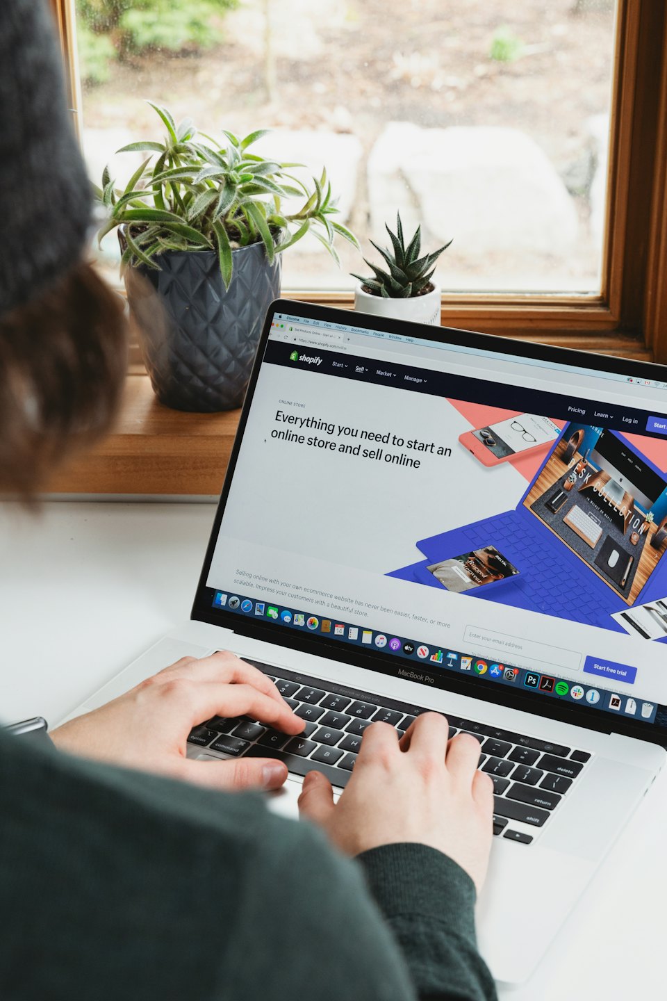 Manos escribiendo en un MacBook Pro con la página web de Shopify abierta.
