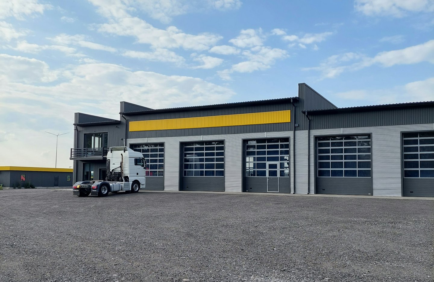 Un tráiler blanco aparcado delante de un edificio industrial moderno.